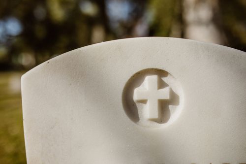Free A detailed view of a carved cross on a marble tombstone in a cemetery. Stock Photo