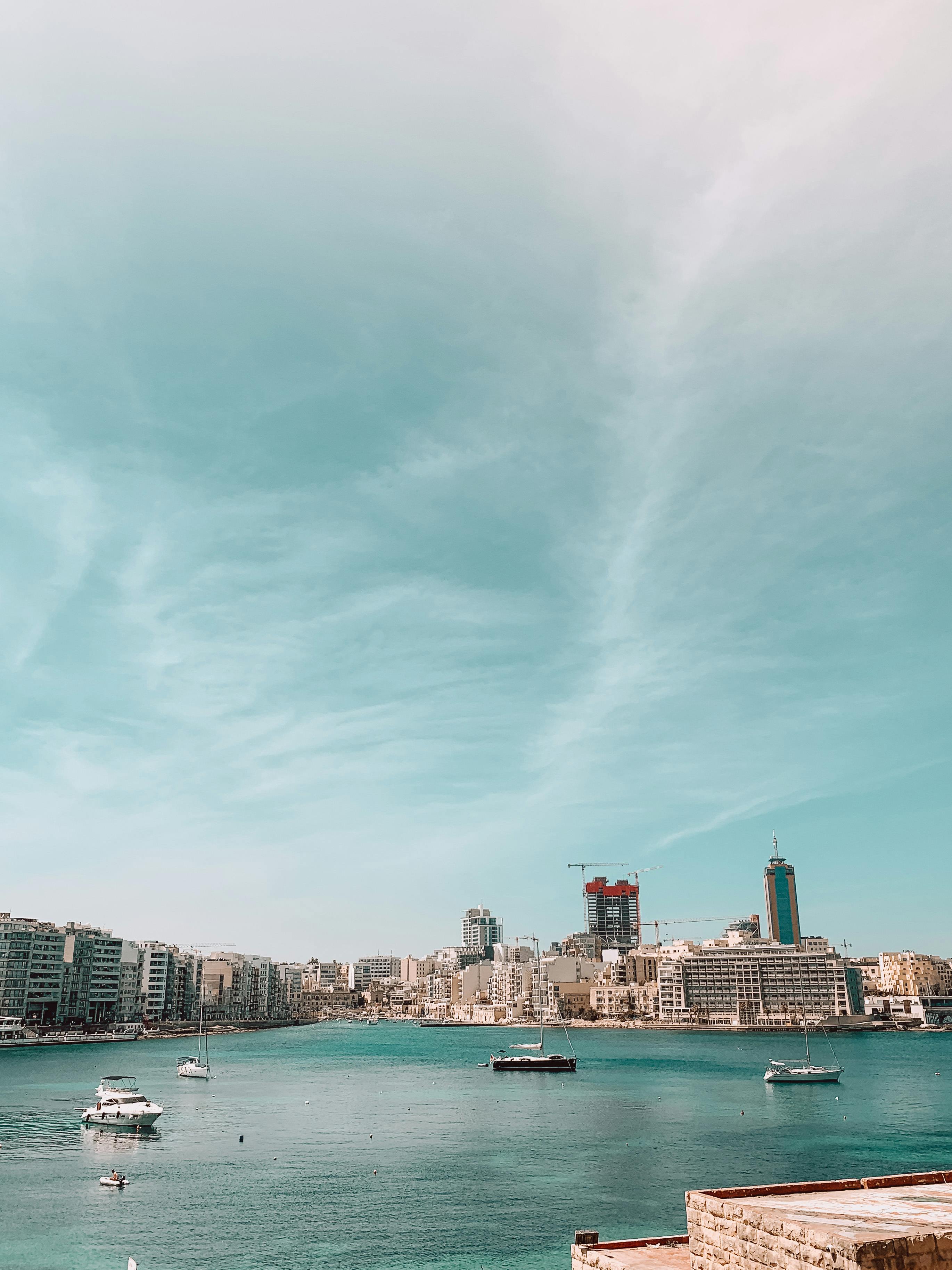 A captivating view of Saint Julian's Bay in Malta with boats and a vibrant skyline under a clear sky.