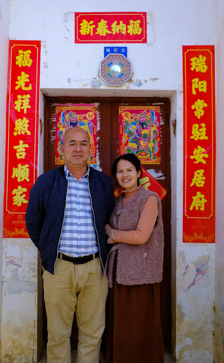 Couple Standing In Front Of The Door Decorated For Vietnamese New Year Celebration 