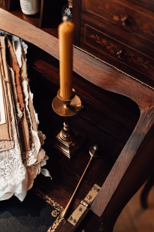Free From above of wax candle on table with carton sheets against wooden chest of drawers with ornament Stock Photo