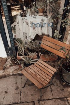 Old chair on pavement against glass wall and potted plants
