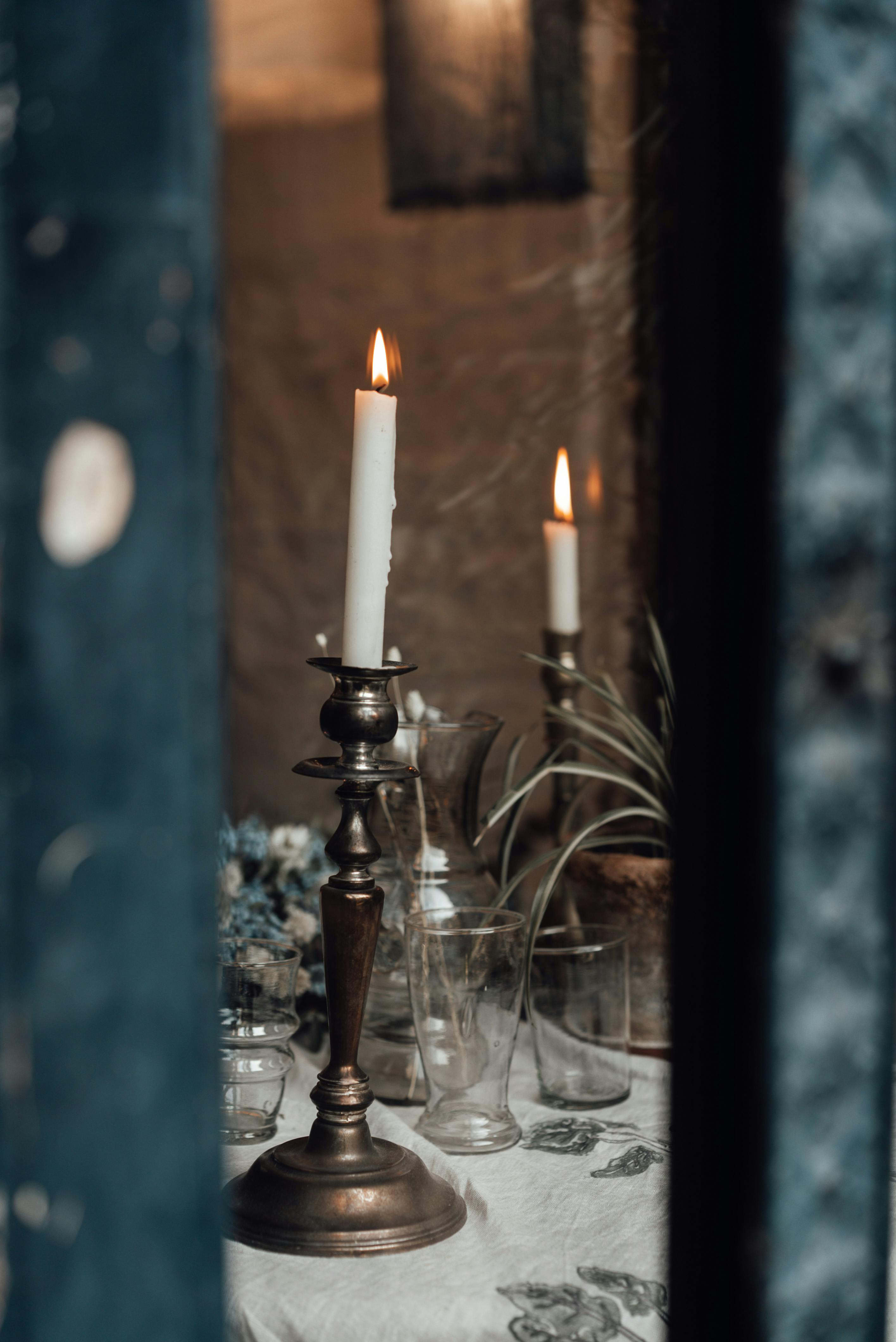 burning candles in candlesticks on table at home