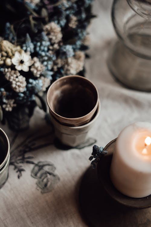 Flower bouquet against old glasses and burning candle on table