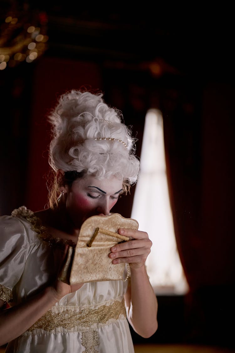 Woman In A Period Costume Holding A Gold Purse