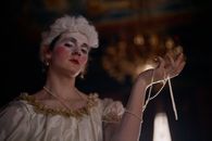 Person in White Dress with Wig Holding Pearl Necklace