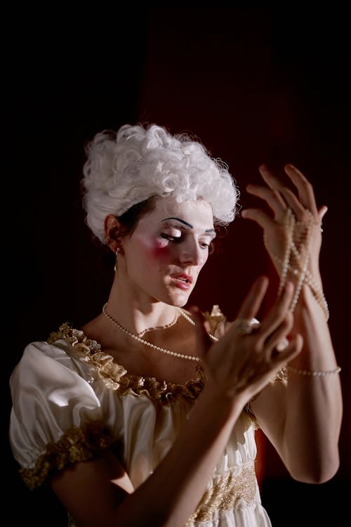 Free A Woman in Costume Looking at the String of Pearls Stock Photo