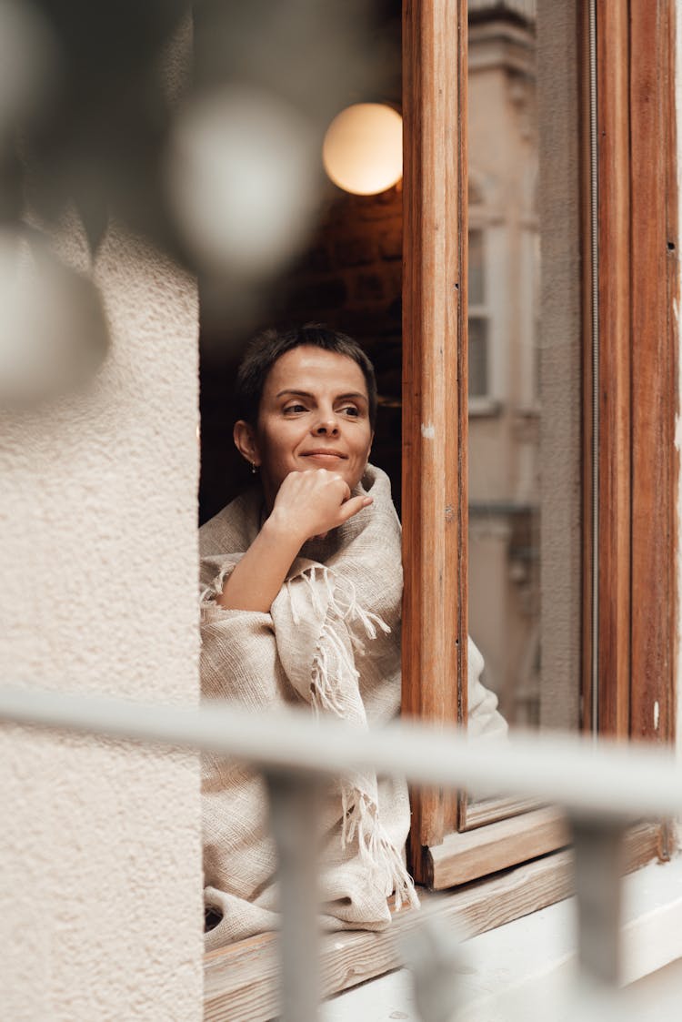 Smiling Woman Looking Out Of Window At Home