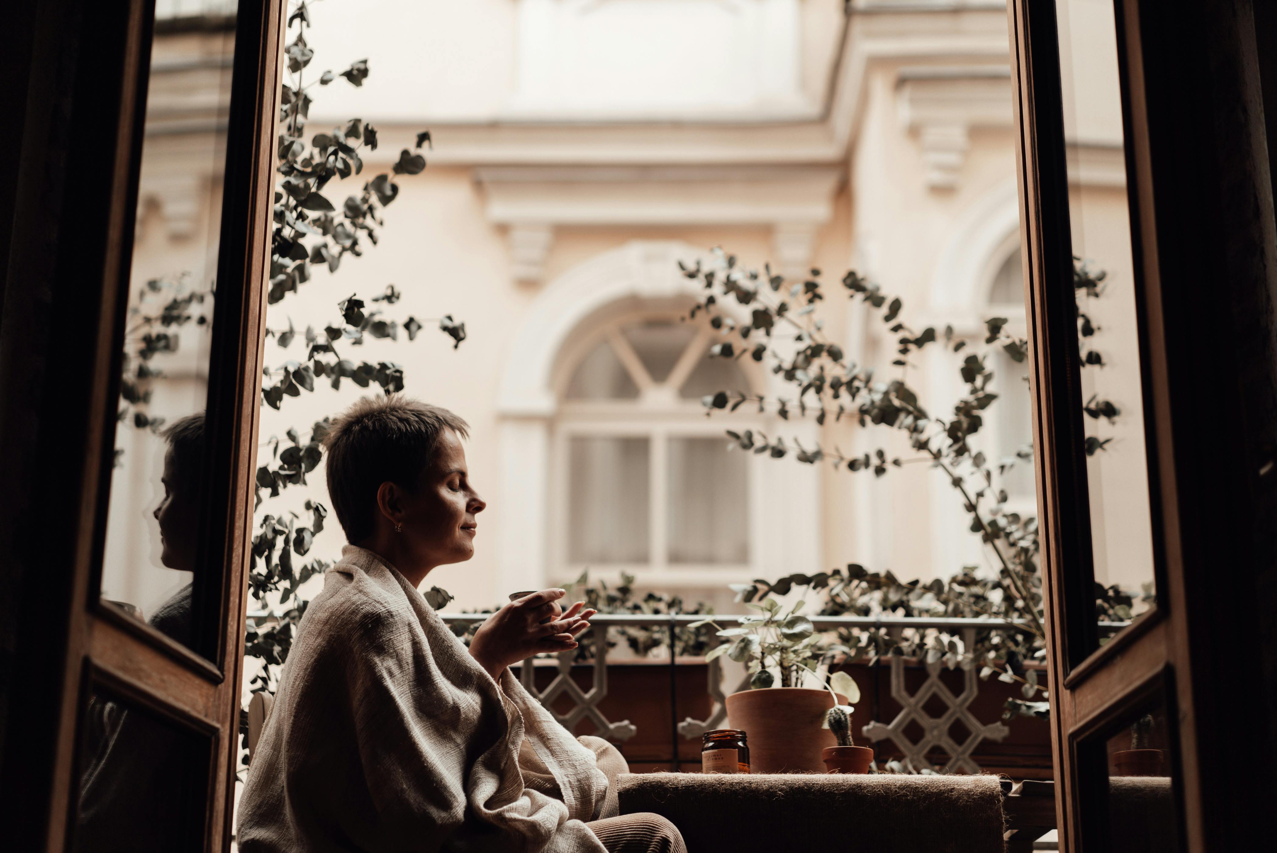 concentrated woman with aromatic coffee on balcony at home