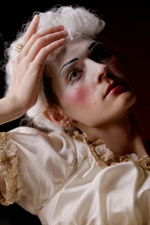 A Woman Wearing Greasepaint and White Wig Looking Up