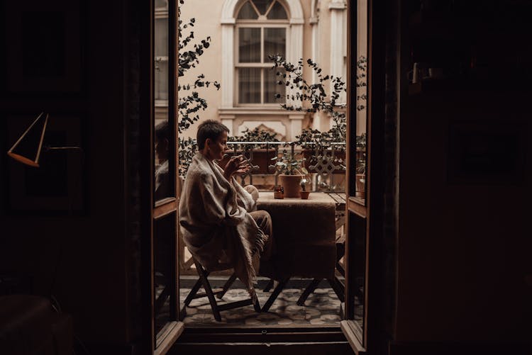 Woman With Coffee Resting On Balcony At Home