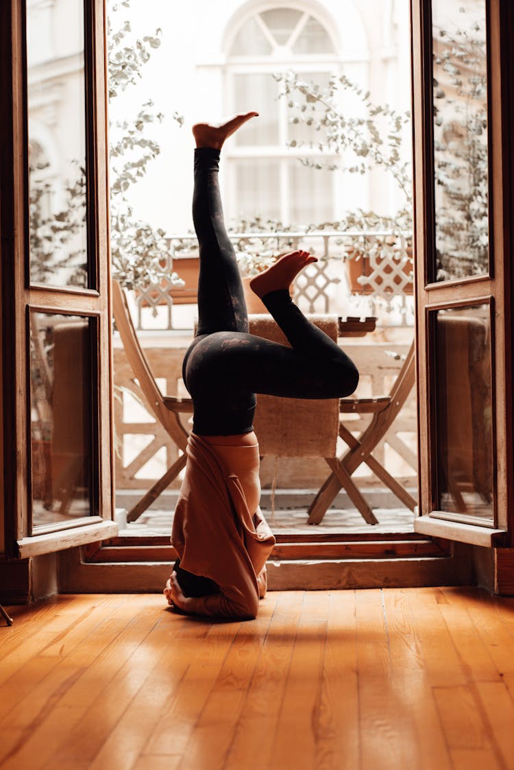 Faceless Person Standing On Head Near Window In Apartment