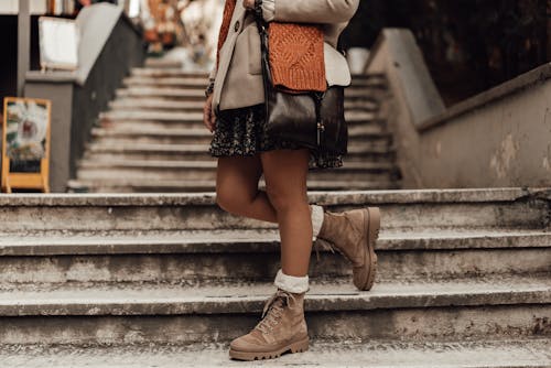Crop woman in warm clothes and skirt on snowy stairs