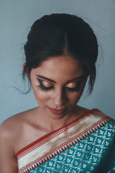 A young Indian woman in a sari with intricate makeup, showcasing elegance.