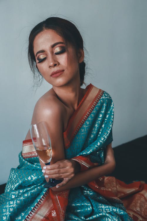 Free A Woman in One Shoulder Top Holding Champagne Glass with Eyes Closed Stock Photo
