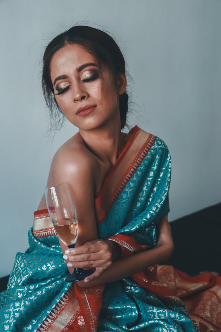 A Woman In One Shoulder Top Holding Champagne Glass With Eyes Closed