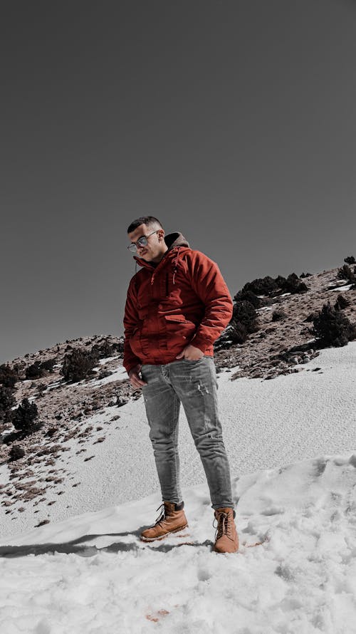 Man in Red Jacket Standing on Snow Covered Ground