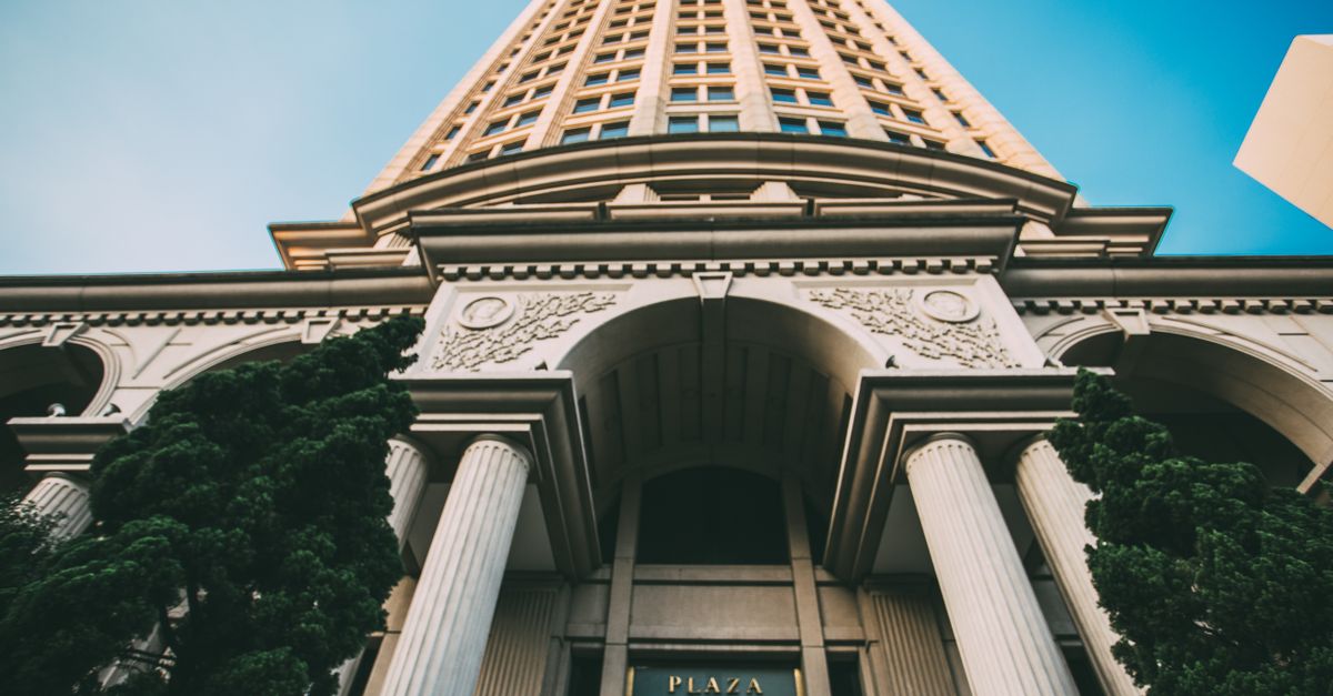 Architectural close-up of a tall building with classical columns against a clear blue sky.