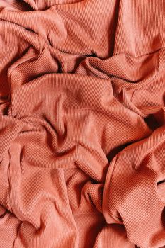 Close-up of a textured coral fabric showcasing unique wrinkles and corduroy design.