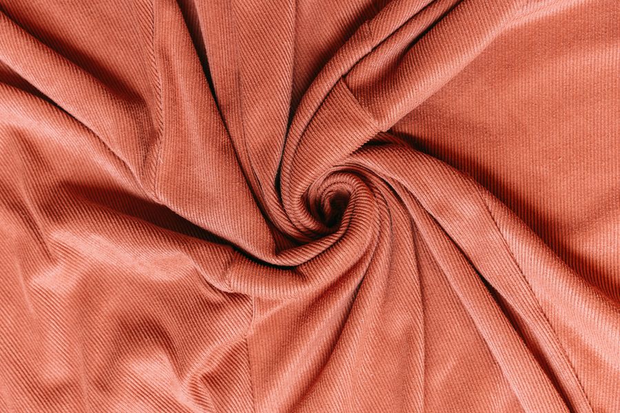 Close-up of terracotta corduroy fabric coiled in a spiral — photo by AI25.Studio on Pexels