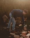 Man with axe and firewood on meadow in countryside