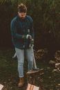Man with axe on stump against hedge