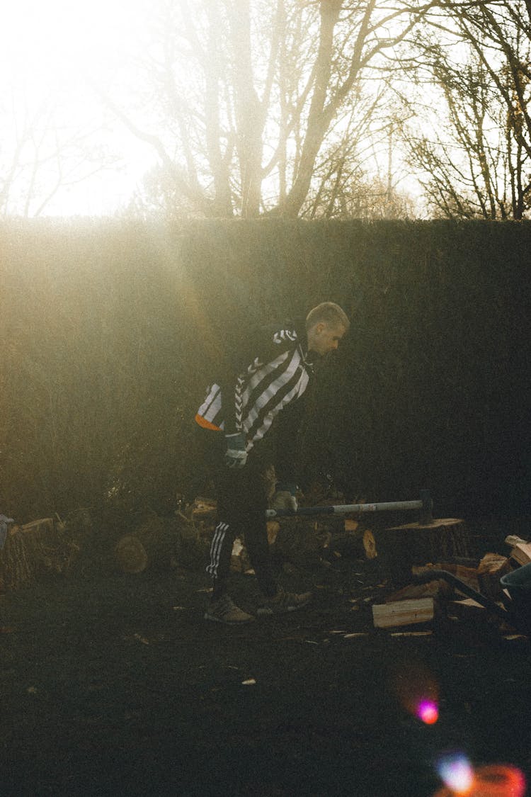 Man Chopping Wood With Axe In Sunshine