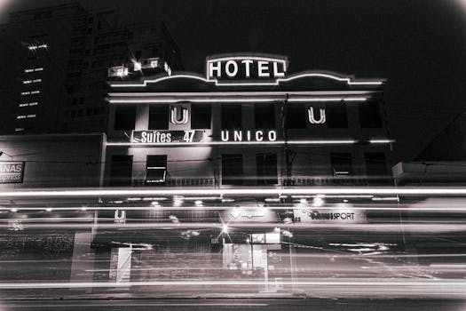 Black and white long exposure of illuminated street with contemporary hotel building with glowing lights located in city at night time