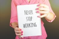 一位女士手持笔记本，上面写着“永远不要停止在室内工作”的励志信息