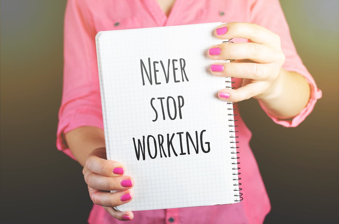 a lady holding a notebook that says "never stop working"