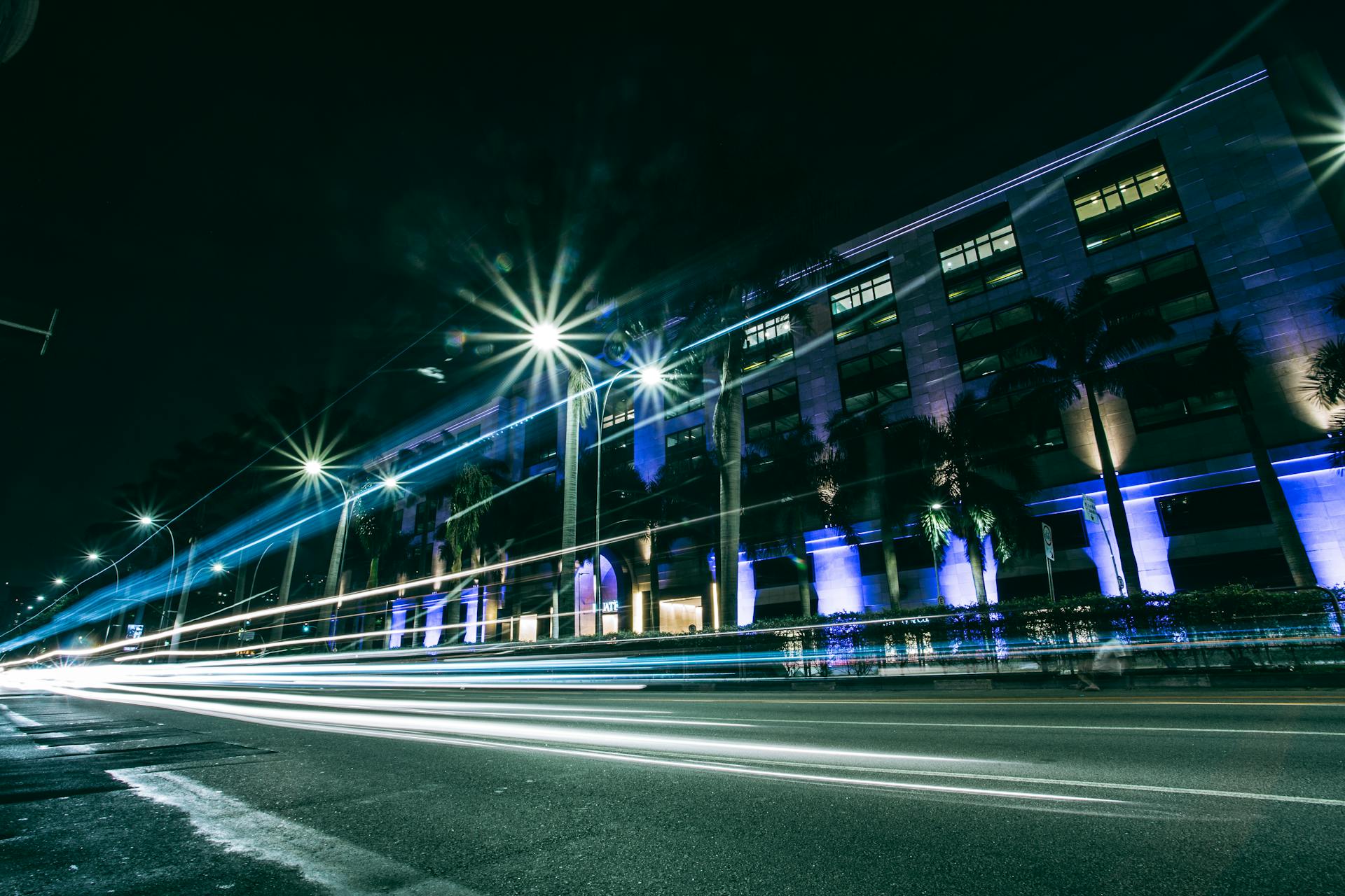 Vibrant urban street scene with light trails from moving traffic, showcasing dynamic city life at night.