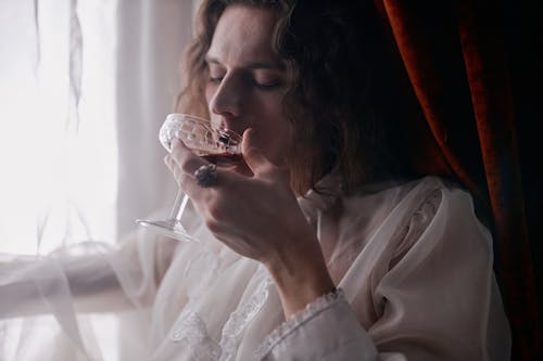 A Person in White Drinking Wine