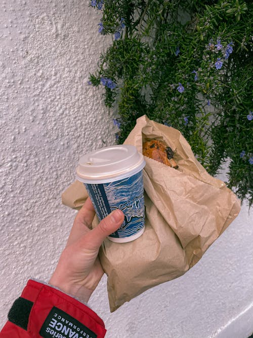Free Person with takeaway coffee and bakery in paper bag Stock Photo