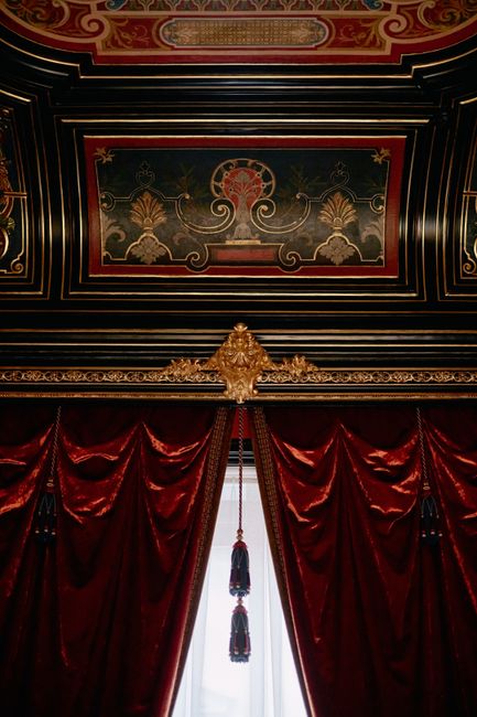 Luxurious velvet curtains with intricate ceiling detail in classic interior design.