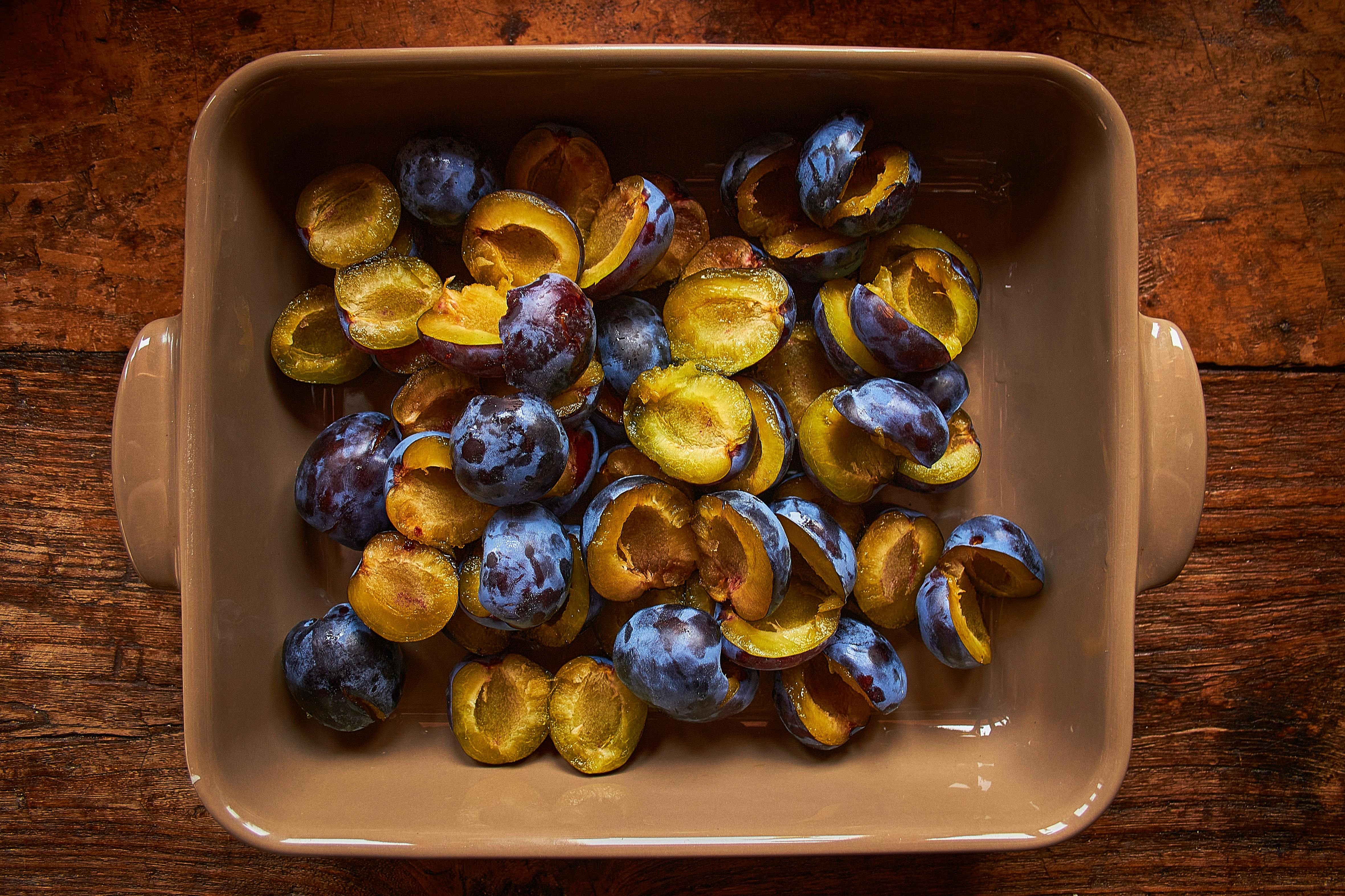 Free A Brown Food Tray with Fresh Prunes Sliced in Halves Stock Photo