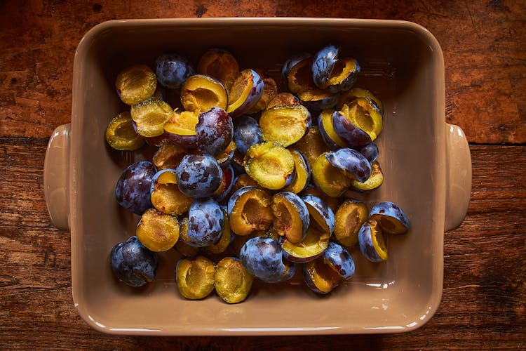 A Brown Food Tray With Fresh Prunes Sliced In Halves