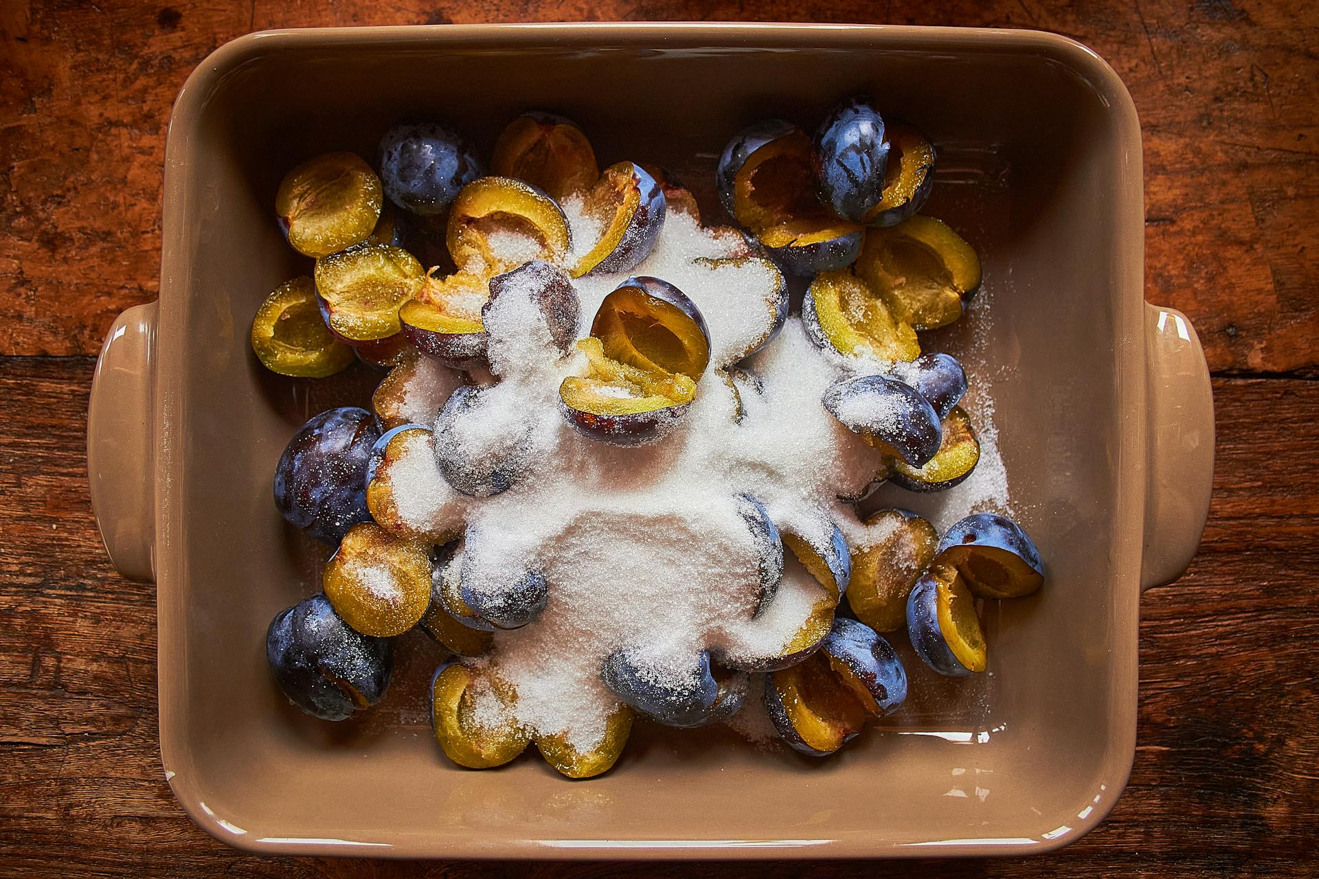 Fresh Sliced Stanley Plums in a Brown Food Tray with White Sugar