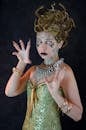 Scary young female model with snake hair in costume of mythological Medusa gesturing with hands and looking away against black background