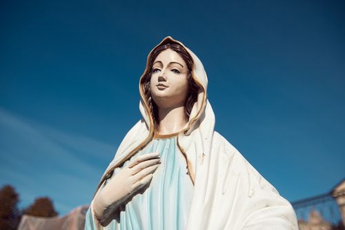 Free A serene statue of the Virgin Mary stands against a clear blue sky, symbolizing peace and faith. Stock Photo