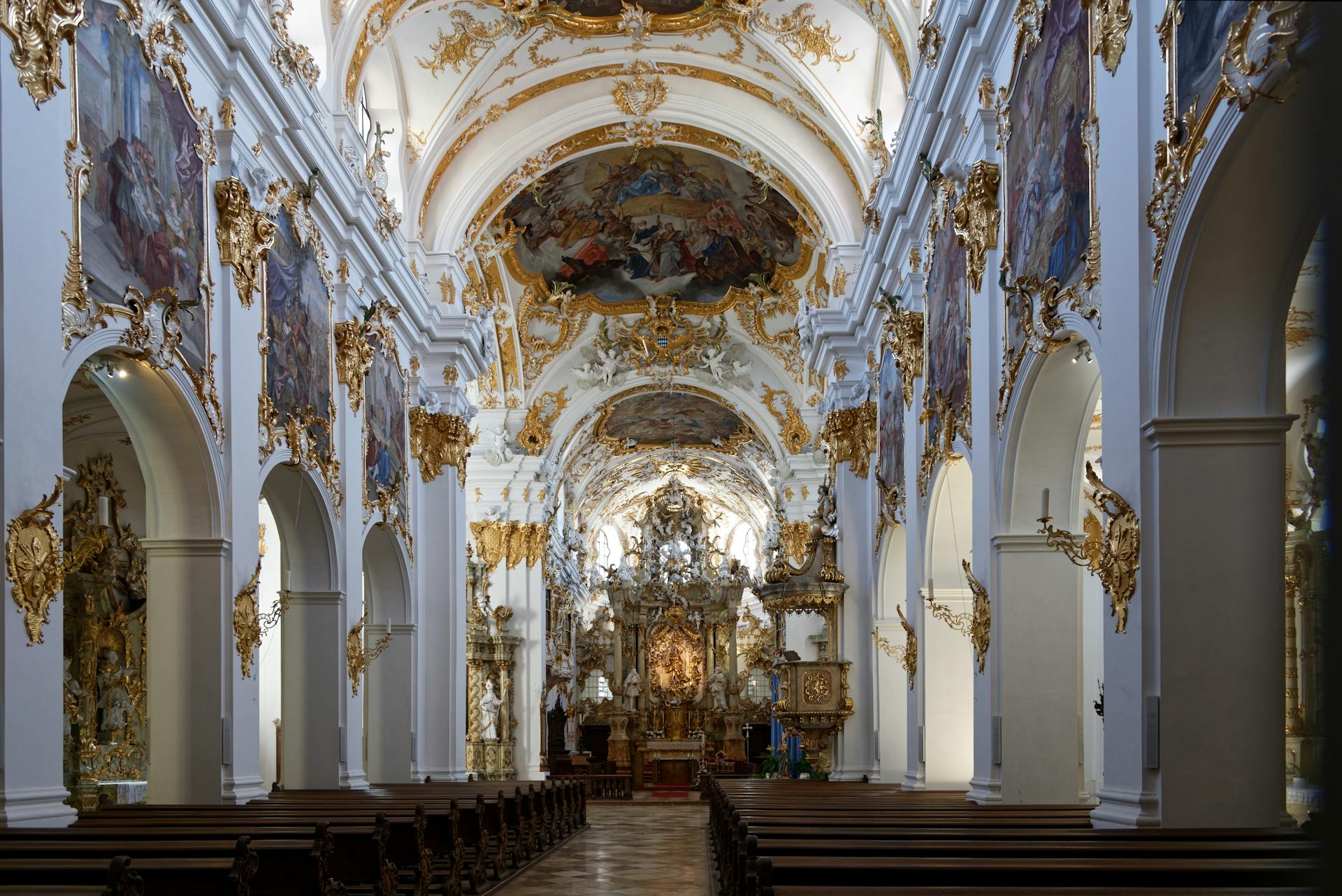 Stunning ornate interior of a Baroque cathedral in Regensburg, Germany, showcasing gilded arches and religious art.