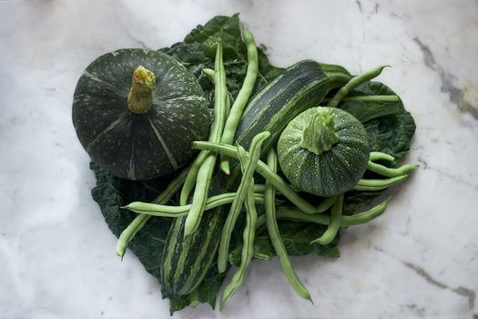 A vibrant display of fresh green vegetables on a marble surface highlighting healthy, nutritious food.