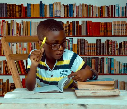 Focused child reading and taking notes in a library setting.