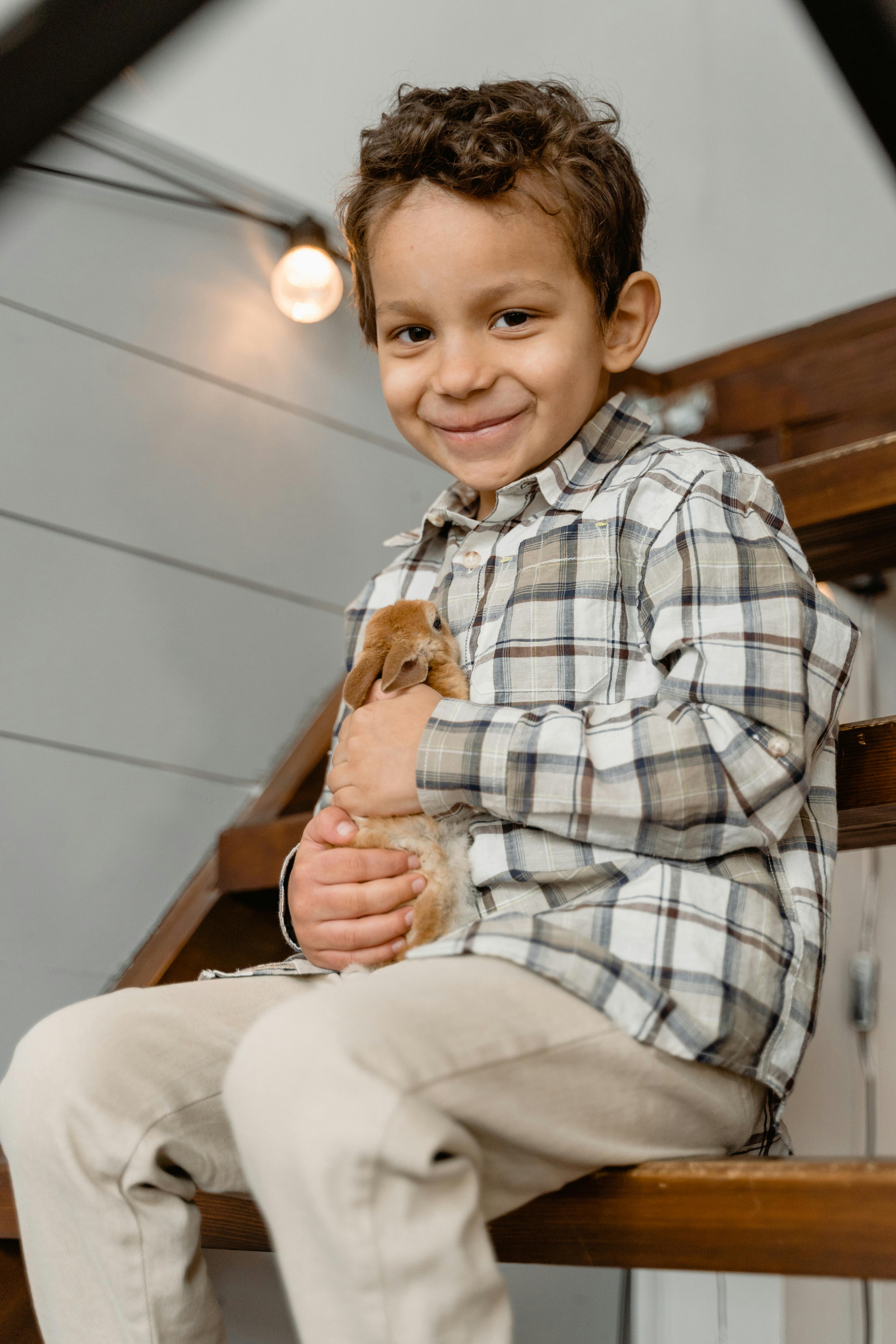 boy sitting on stairs while holding a rabbit