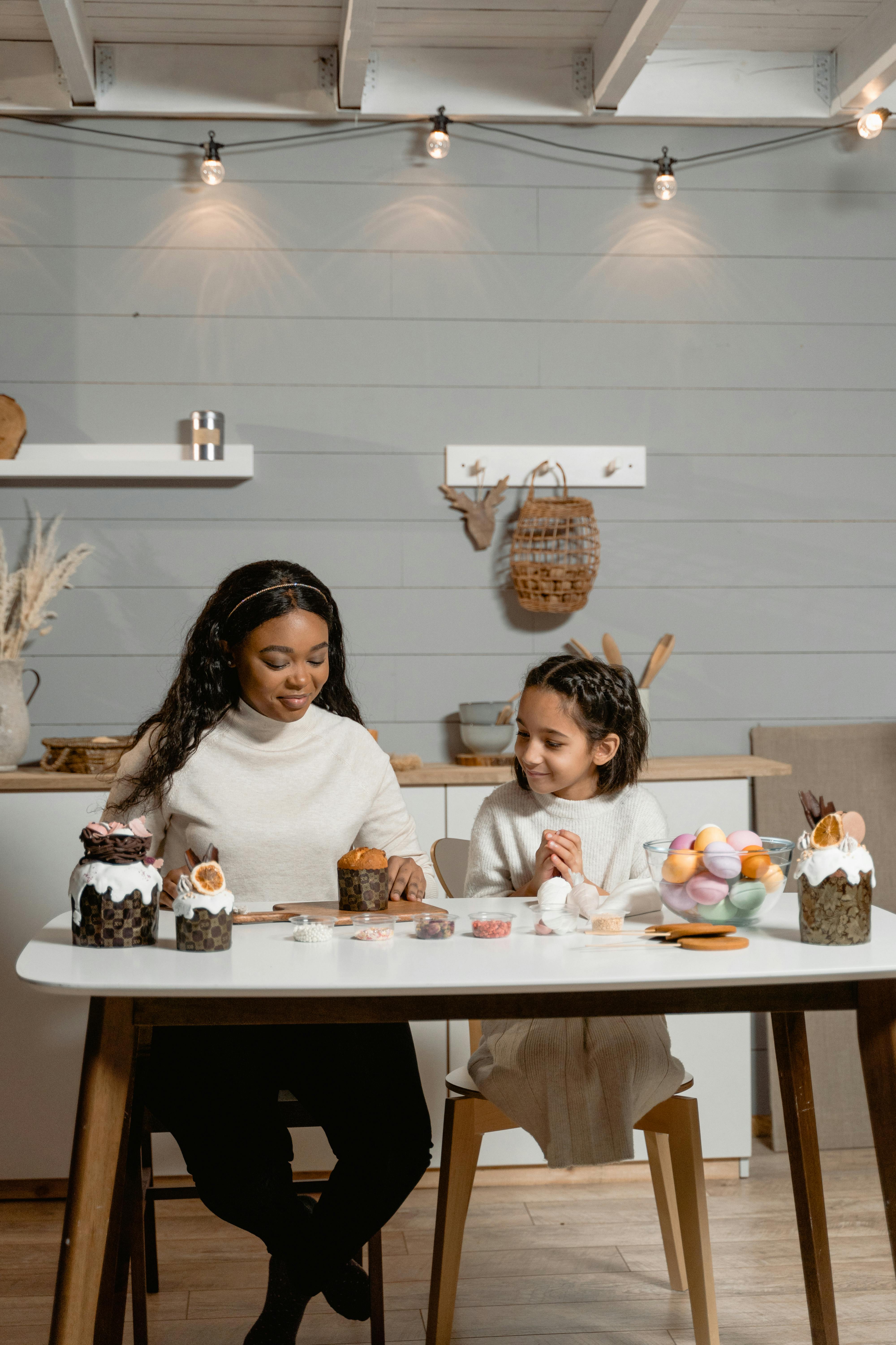 A mother and daughter decorate Easter cupcakes together in a cozy kitchen setting.