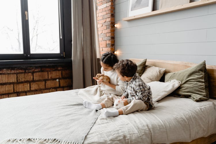 Kids Sitting On Bed Holding Rabbits