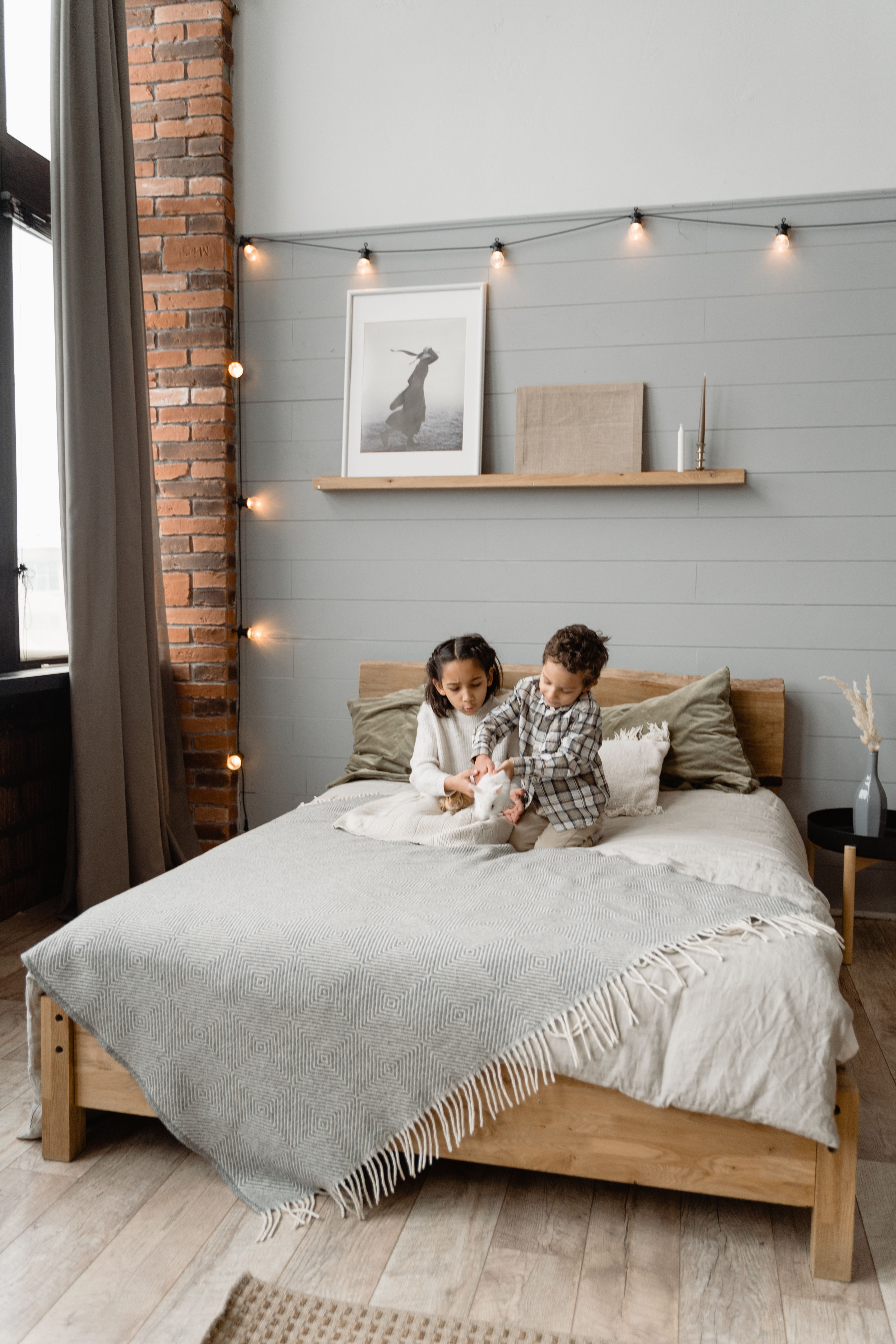 Children playing on a cozy bed in a beautifully decorated room with soft lighting.