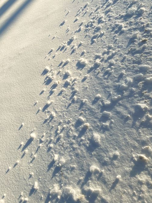 Free Close-up of textured snow with long shadows creating an abstract winter scene. Stock Photo