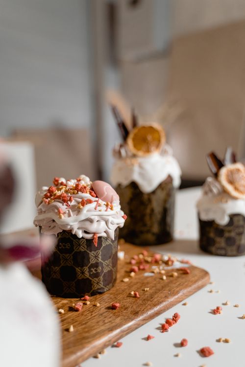 Free A selection of beautifully decorated cupcakes with whipped cream and dried fruit toppings on a wooden board. Stock Photo