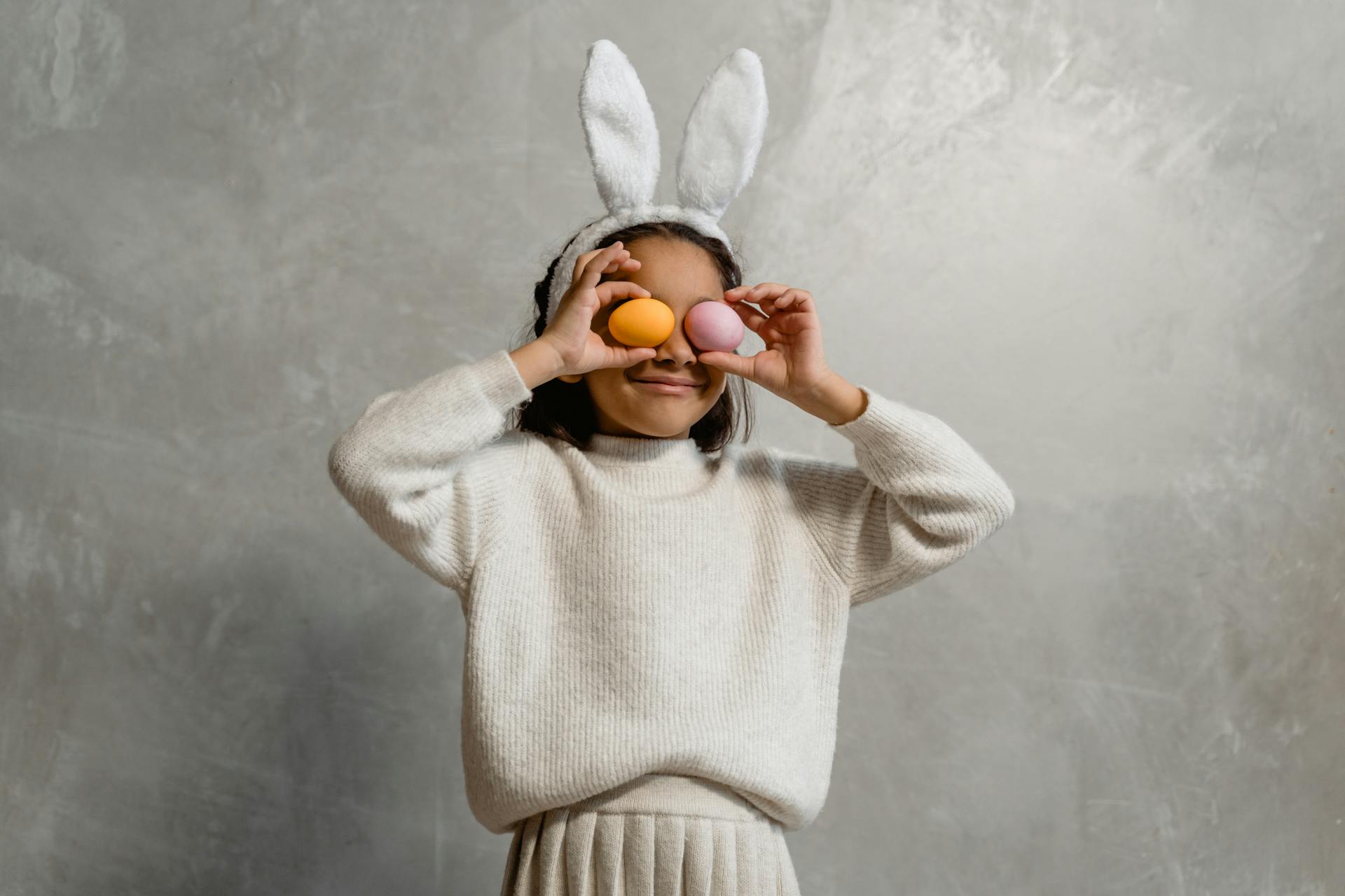 Young girl with bunny ears holding Easter eggs, joyful springtime celebration.