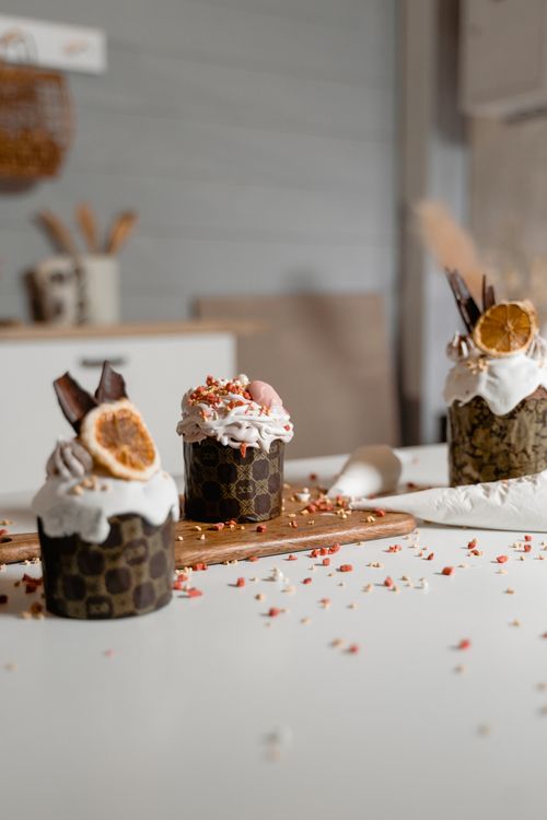 Free Three artisanal cupcakes with dried citrus and chocolate toppings on a wooden board. Stock Photo