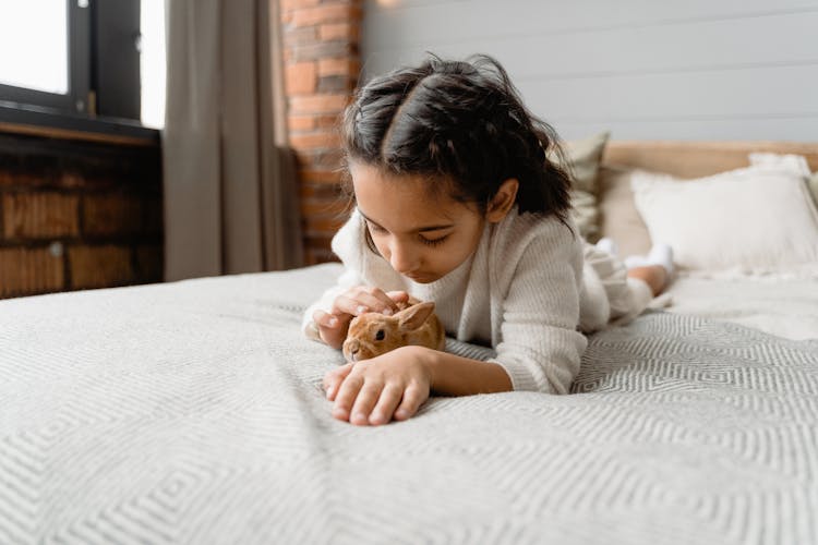 A Kid Lying On Front Petting A Rabbit